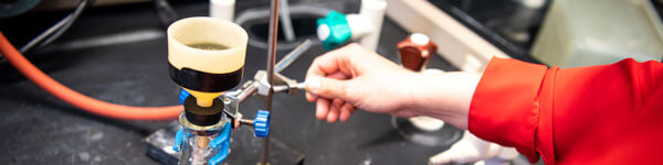 A student turns on a Bunsen burner in the lab.